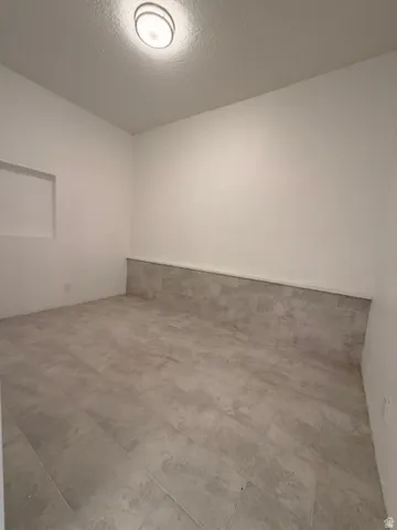Recessed wall niche, flush-mount ceiling light fixture, and large format tile flooring