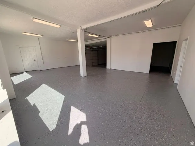 Spacious interior featuring a gray speckled epoxy floor, white painted walls, and overhead fluorescent lighting