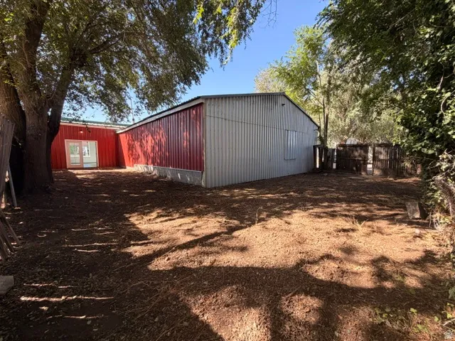 Red and gray metal-sided structure with a gabled roof and light-toned double doors