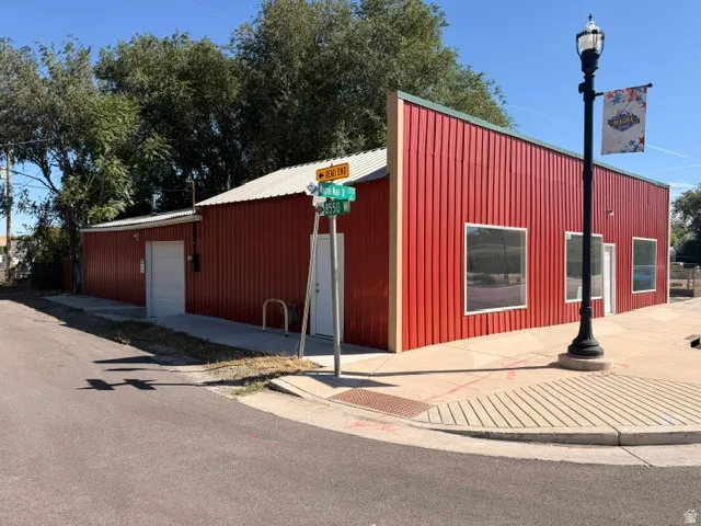 Red corrugated metal siding, storefront windows, white entry door, white garage door, paved corner lot
