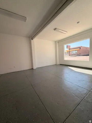 Open-concept interior featuring painted concrete flooring, recessed lighting, and a large street-facing window