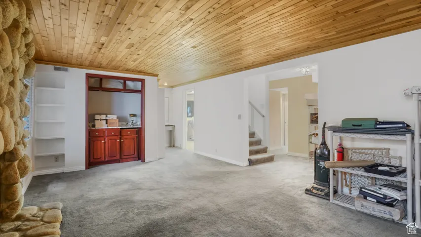 Living room with stairs, carpet floors, and wooden ceiling