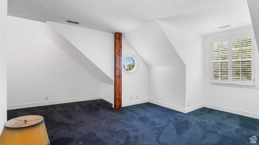 Bonus room featuring dark carpet and lofted ceiling
