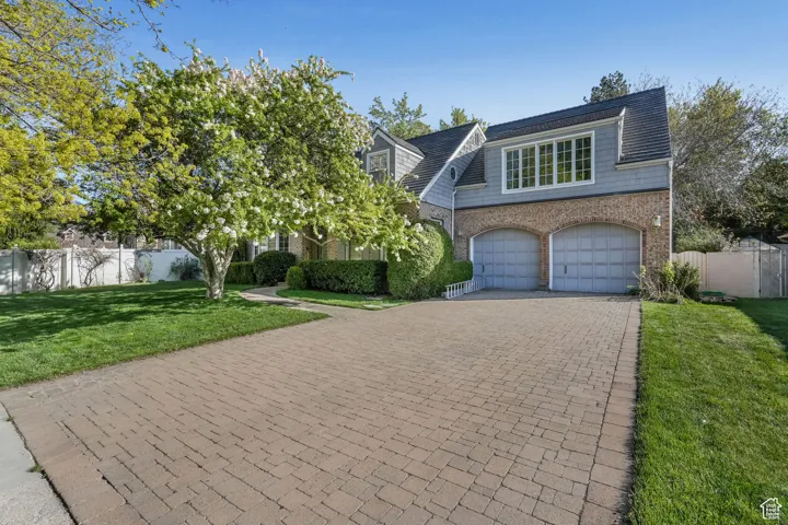 View of front facade featuring brick siding, decorative driveway, and a garage