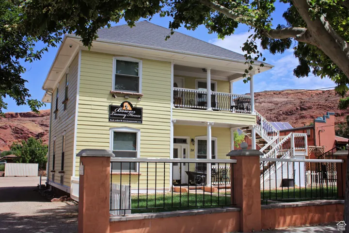 Rear view of property featuring a porch, a mountain view, a fenced front yard, stairway, and a balcony
