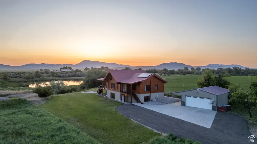 View of front of house with driveway, a front lawn, a detached garage, and solar panels