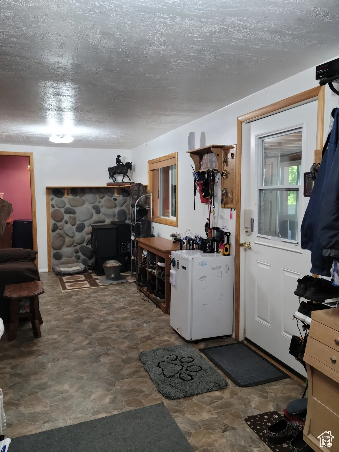 Stone finish flooring, mini fridge, a textured ceiling, and a pellet stove