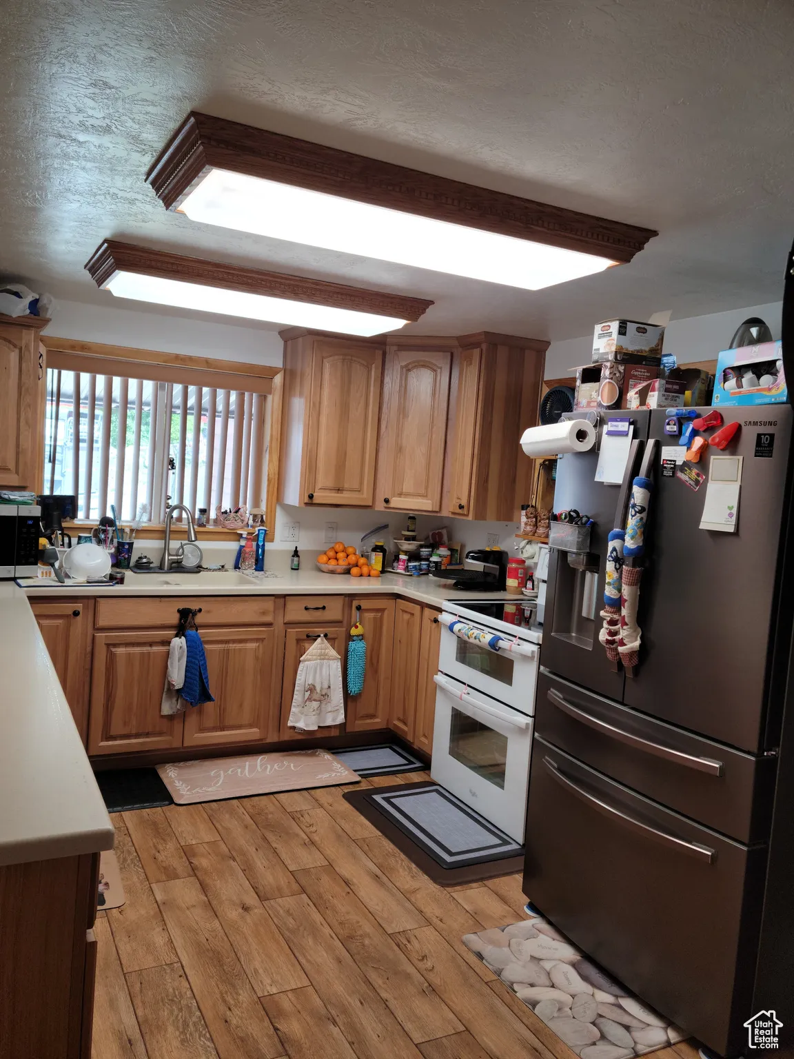 Kitchen featuring stainless steel appliances, light countertops, light wood-style floors, and a textured ceiling