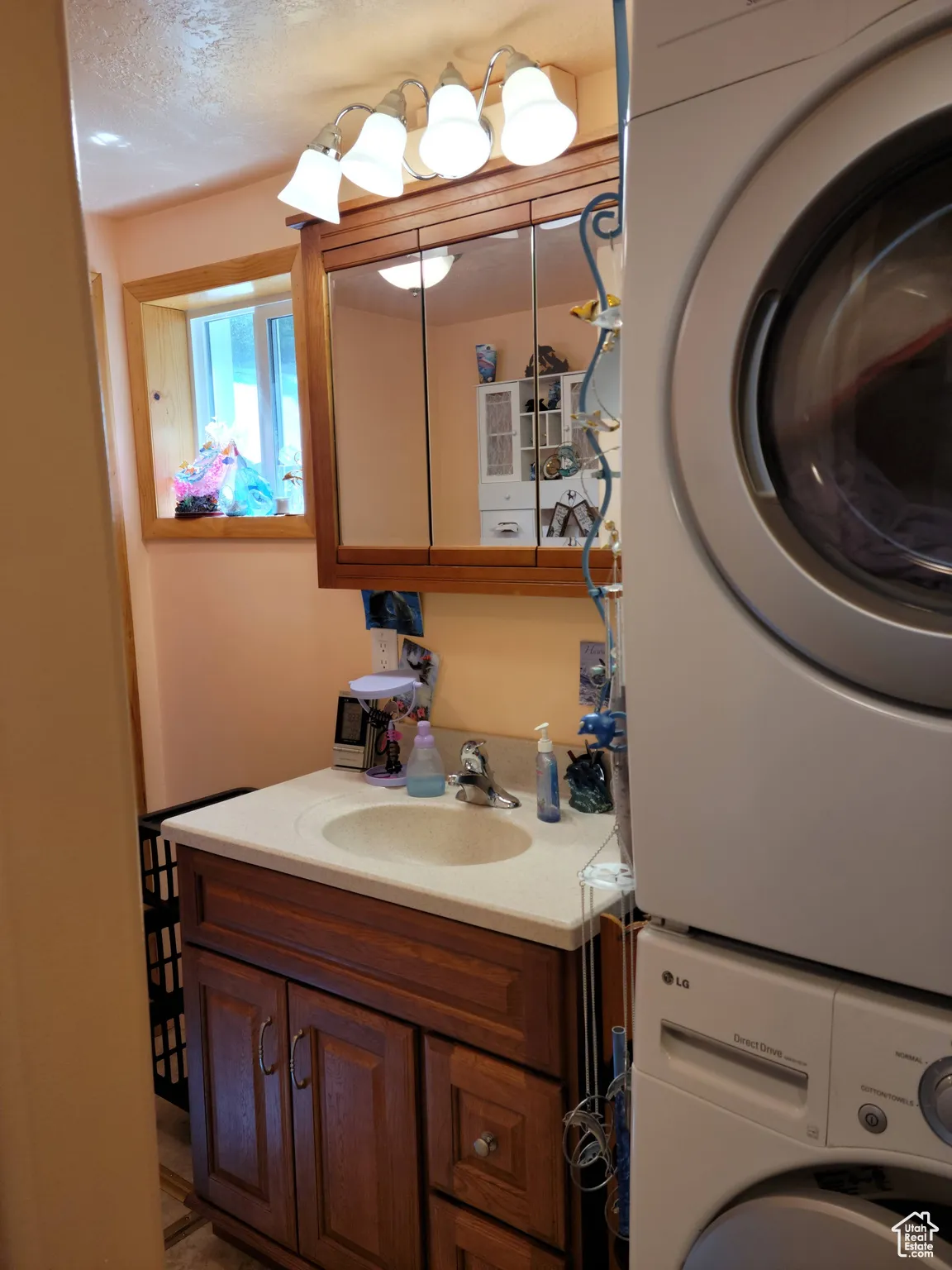 Bathroom with stacked washer / drying machine, vanity, and a textured ceiling