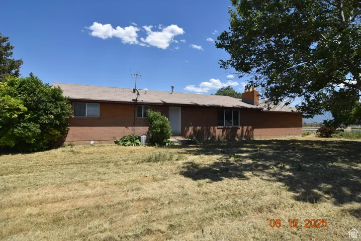 Back of house featuring brick siding, a yard, and a chimney