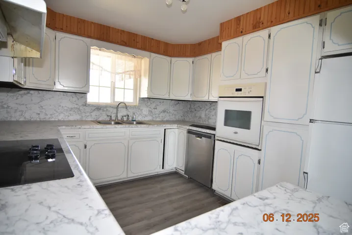 Kitchen featuring white appliances backsplash, light countertops, and white cabinets, wall oven, dishwasher and sink