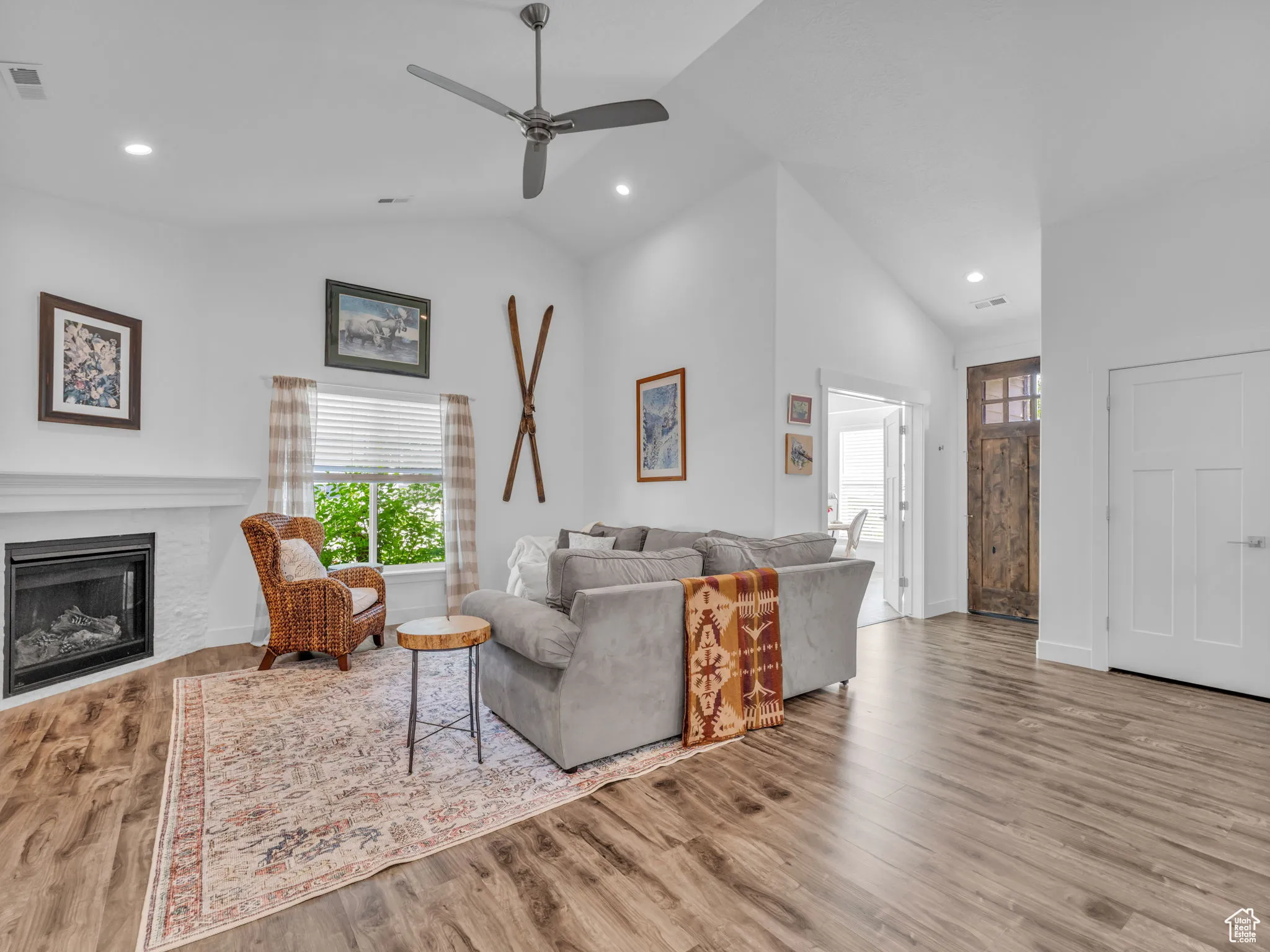 Living area with ceiling fan, a fireplace, recessed lighting, wood finished floors, and high vaulted ceiling