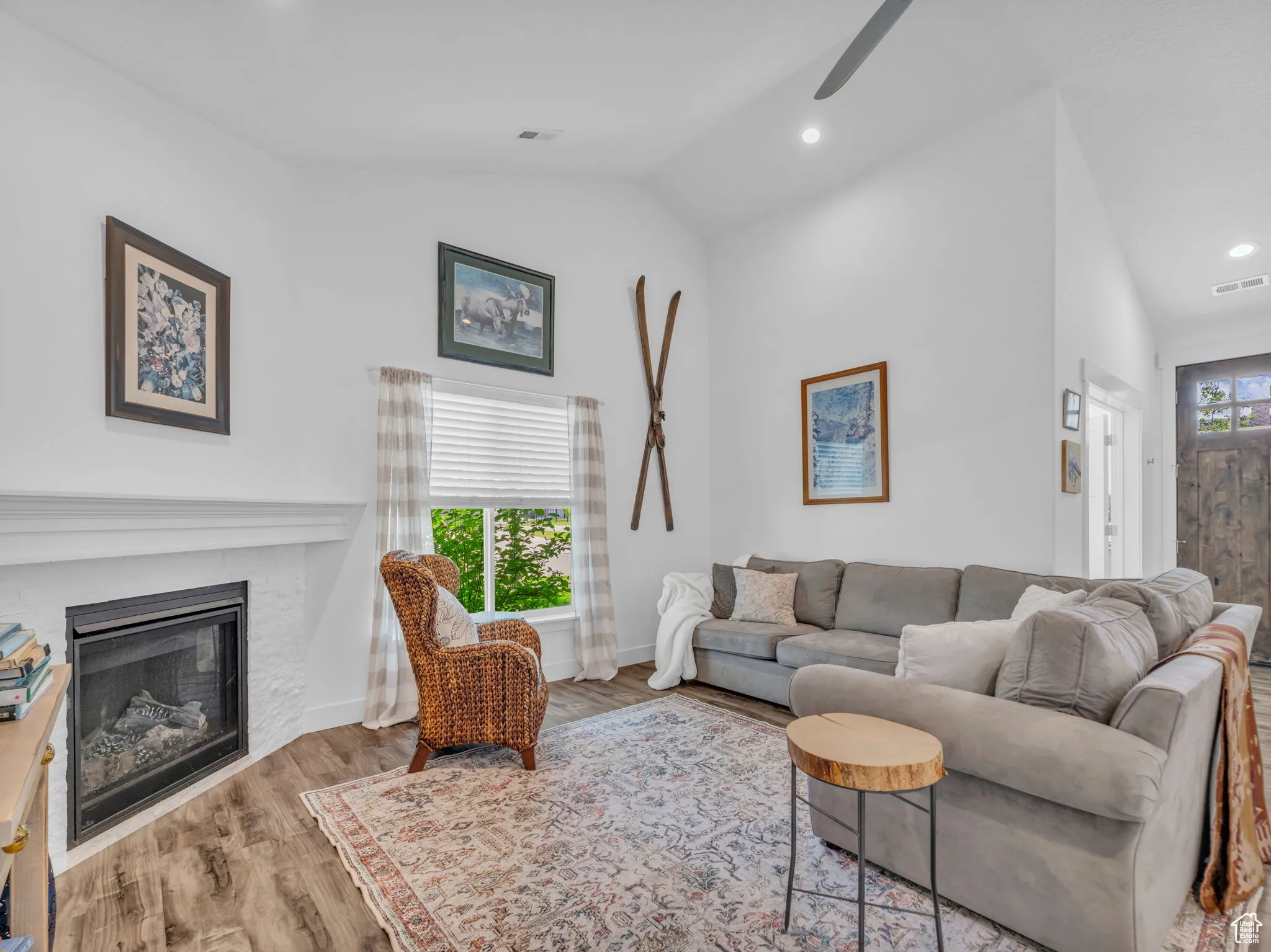Living area with lofted ceiling, ceiling fan, a glass covered fireplace, wood finished floors, and recessed lighting