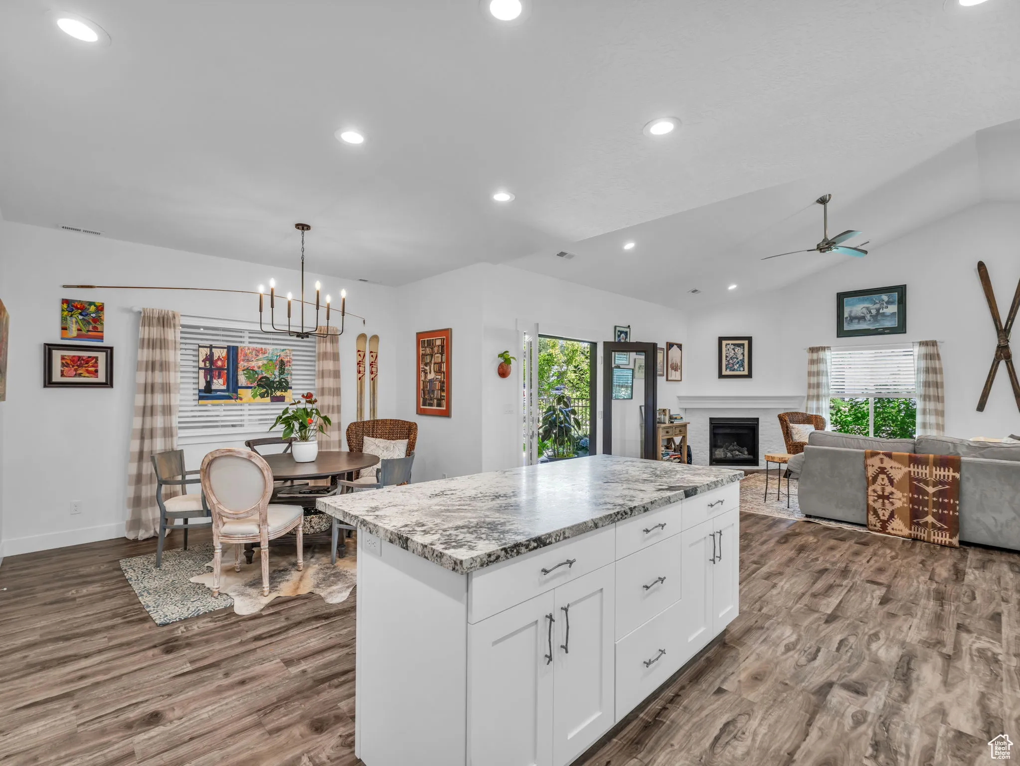 Kitchen with healthy amount of natural light, dark wood-style floors, a fireplace, white cabinets, and lofted ceiling