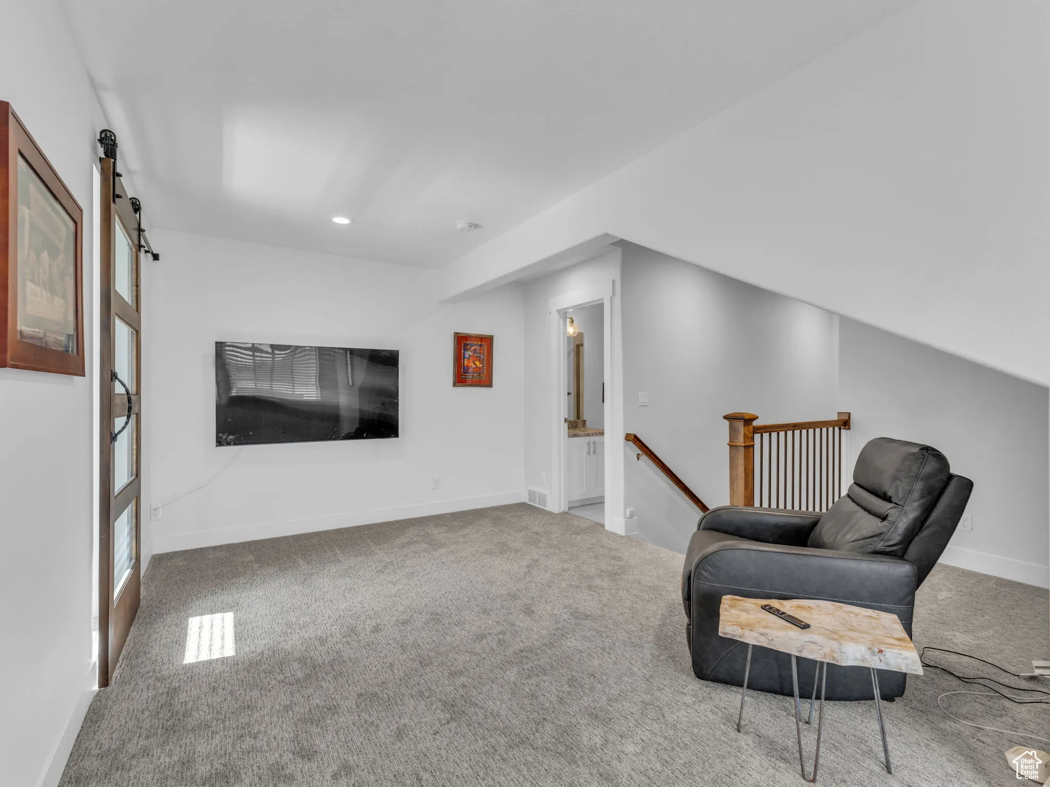 Living area featuring an upstairs landing, carpet, a barn door, and recessed lighting