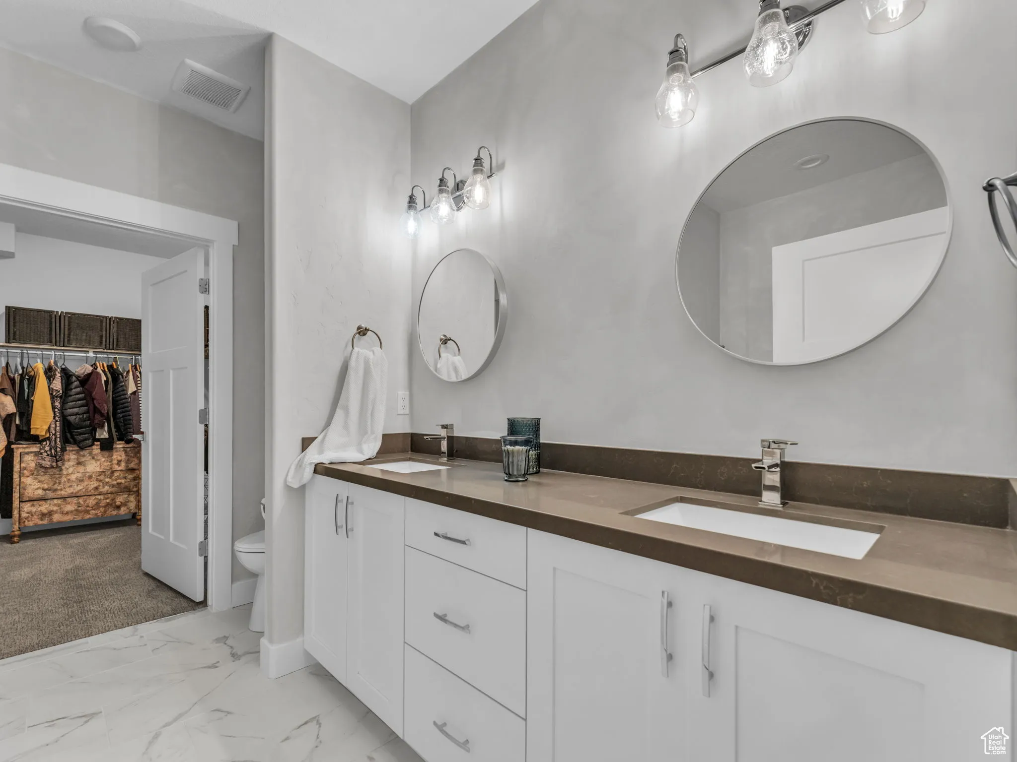 Bathroom featuring double vanity, marble finish flooring, and a spacious closet