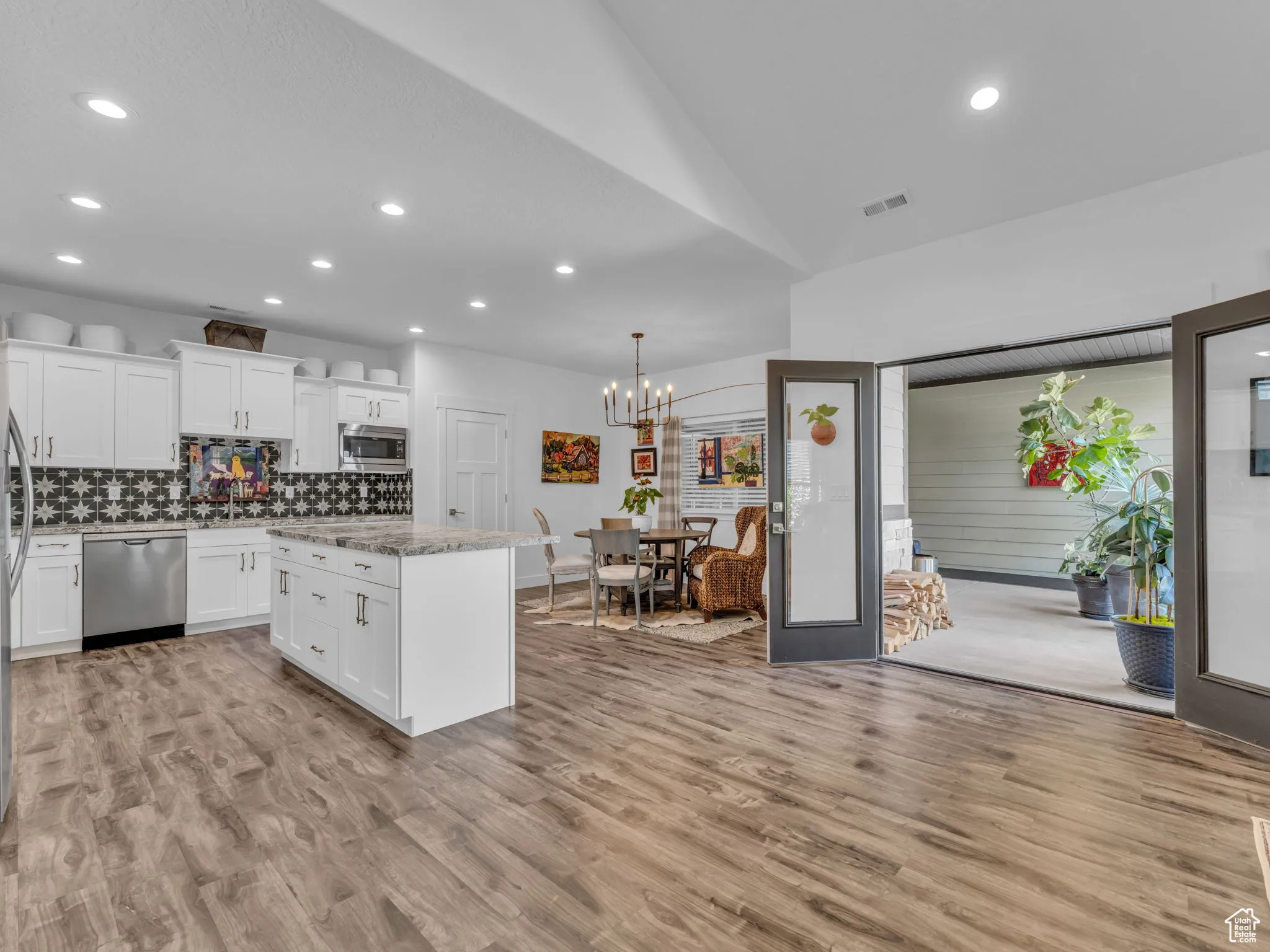 Kitchen with stainless steel appliances, a kitchen island, recessed lighting, backsplash, and light wood finished floors