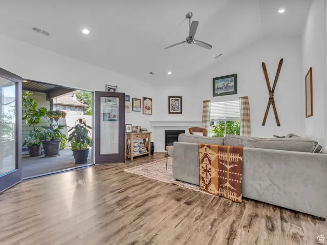 Living room with vaulted ceiling, ceiling fan, wood finished floors, plenty of natural light, and recessed lighting