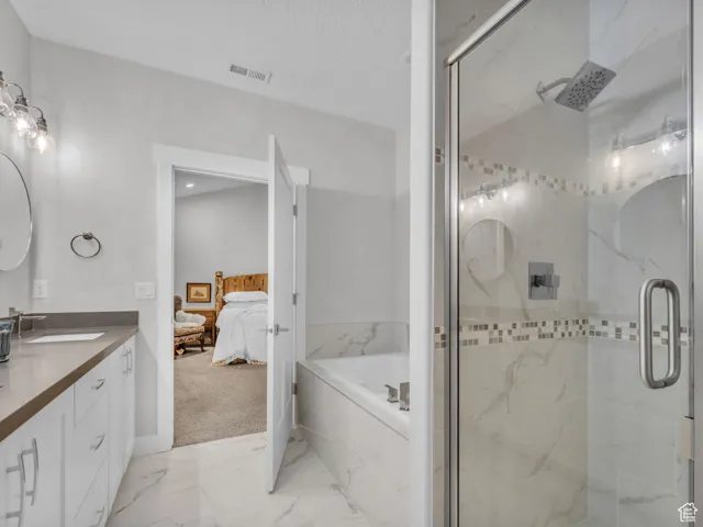 Bathroom featuring vanity, a garden tub, a marble finish shower, ensuite bath, and marble finish floors