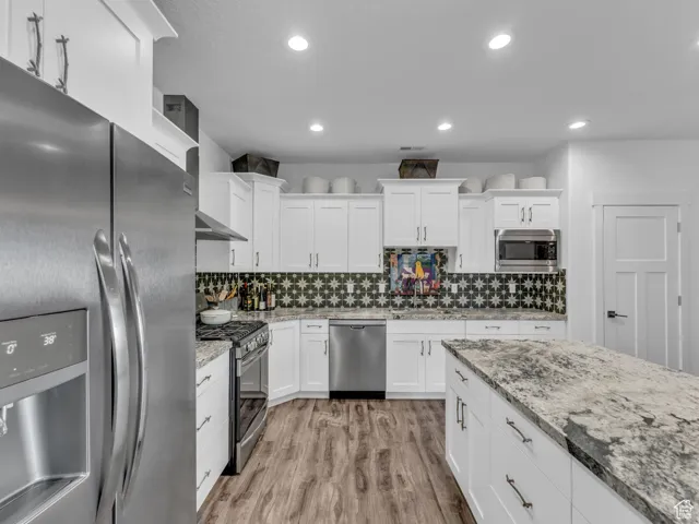 Kitchen with stainless steel appliances, white cabinets, light wood-type flooring, and recessed lighting