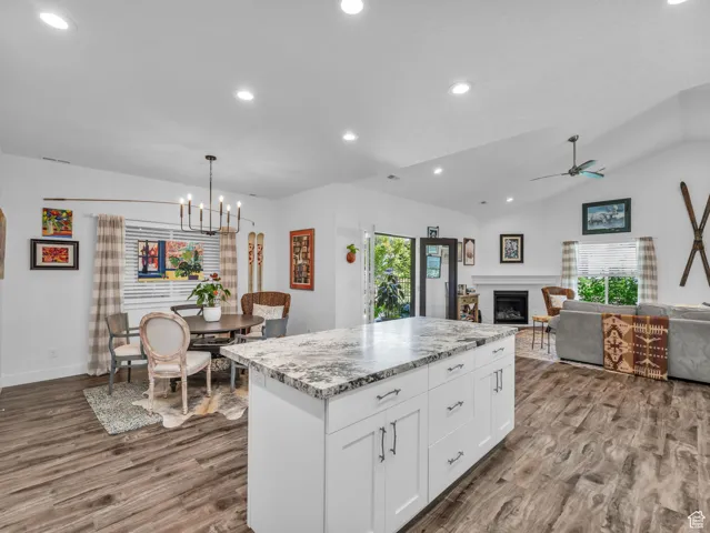 Kitchen with healthy amount of natural light, dark wood-style floors, a fireplace, white cabinets, and lofted ceiling