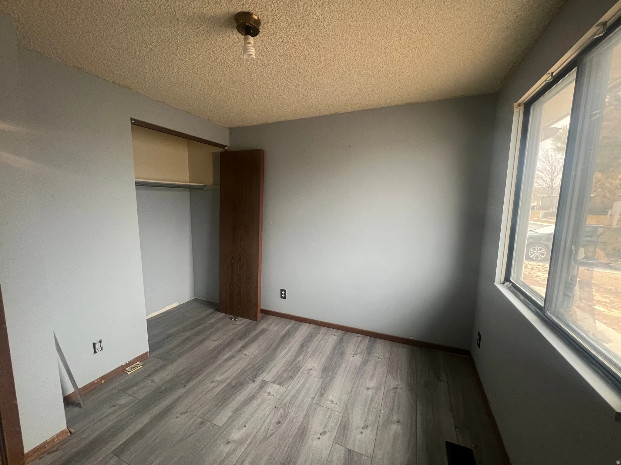 Unfurnished bedroom featuring light wood finished floors, a closet, and a textured ceiling