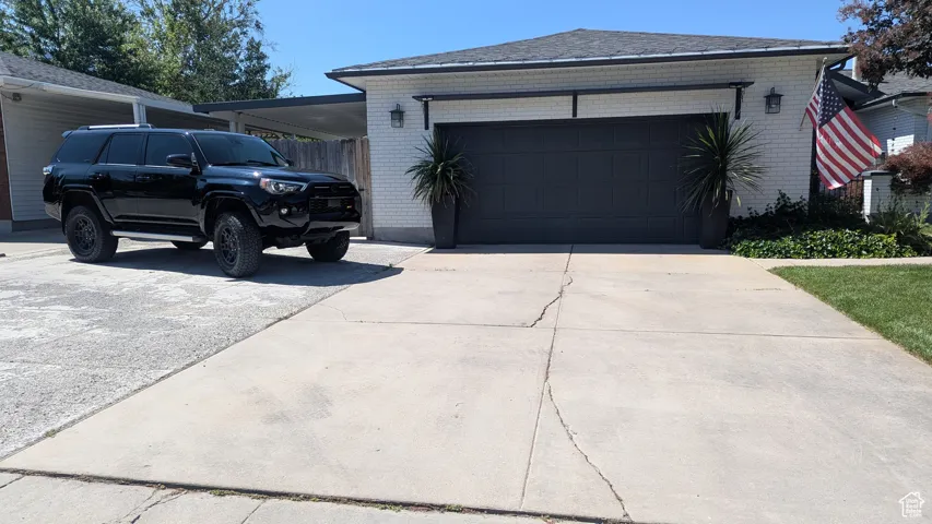 View of property exterior with brick siding, driveway, and an attached garage