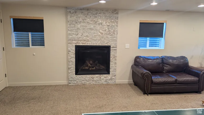 Living room featuring carpet, recessed lighting, and a stone fireplace