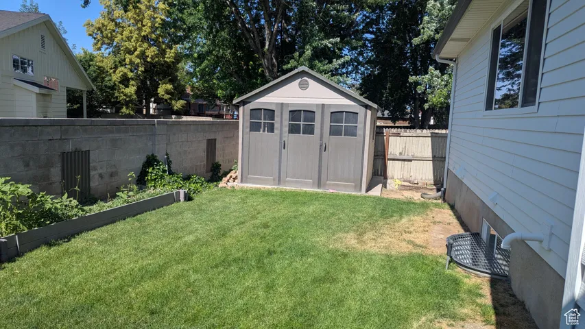 Fenced backyard featuring a storage shed