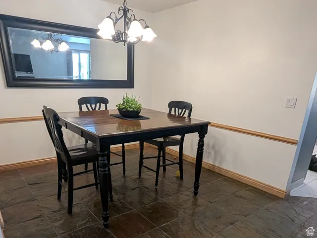 Dining space featuring dark stone finish floors and a chandelier