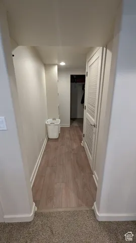 Corridor with wood finished floors and recessed lighting