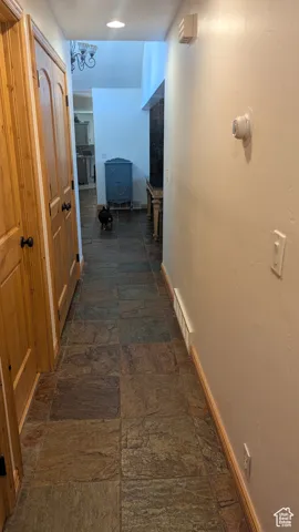 Corridor featuring baseboards and stone tile floors