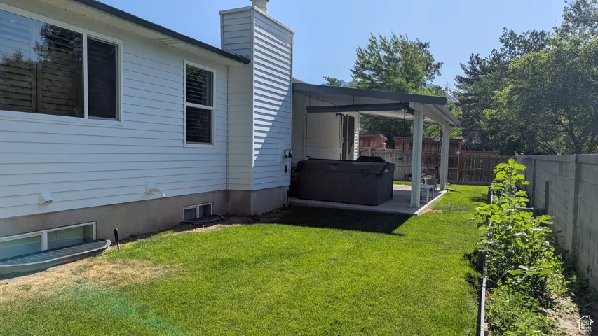 Fenced backyard featuring a hot tub and a patio area