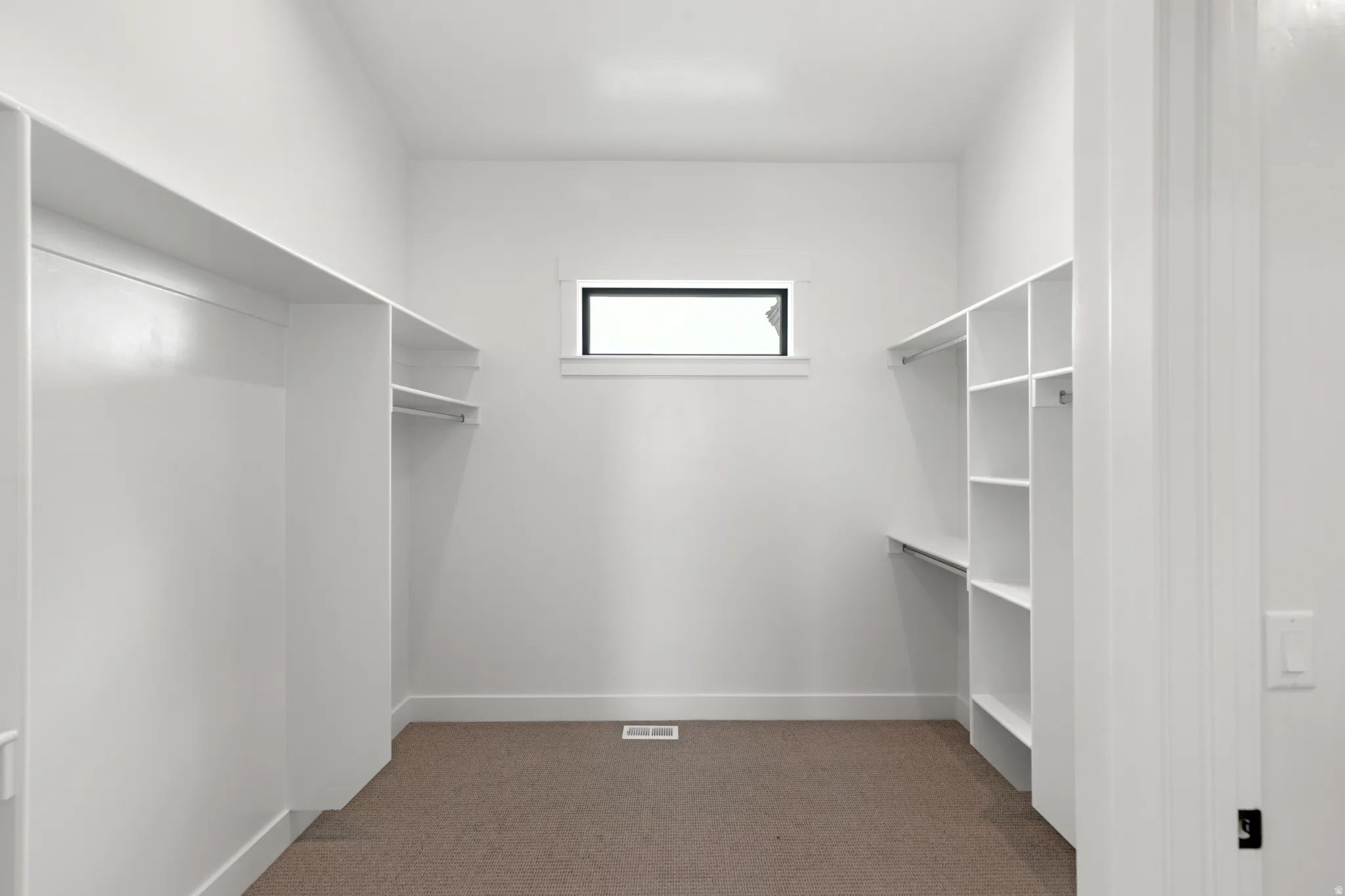 Built-in white shelving, integrated hanging rods, and a window for natural light