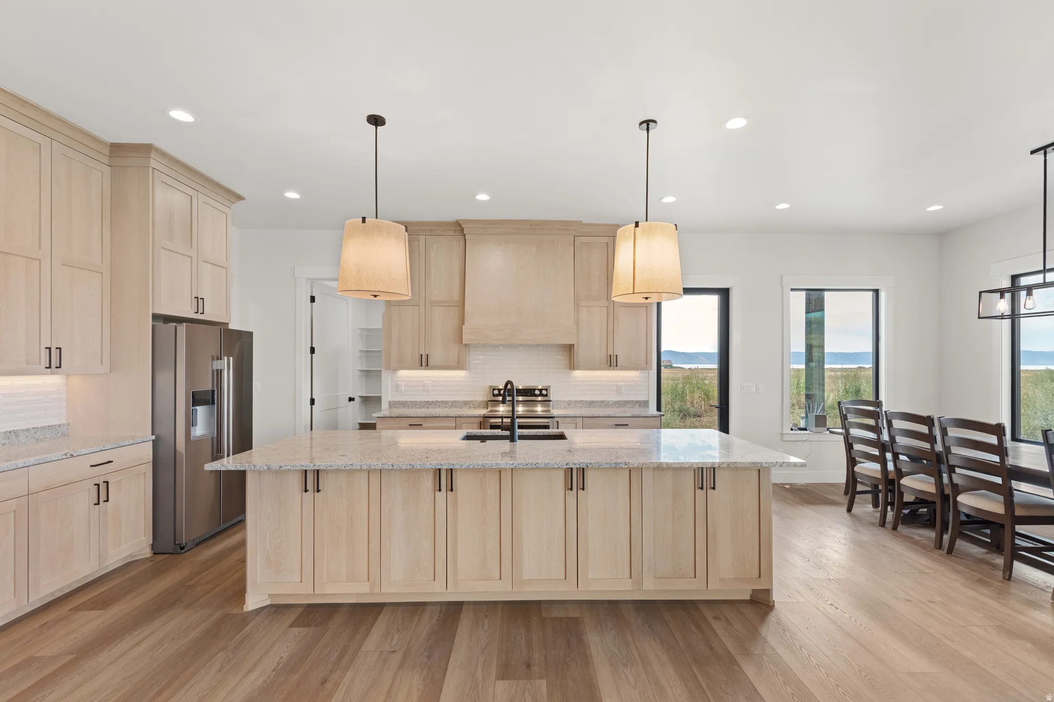 Kitchen featuring light wood-finish cabinetry, a large center island with a light-toned countertop, and stainless steel appliances