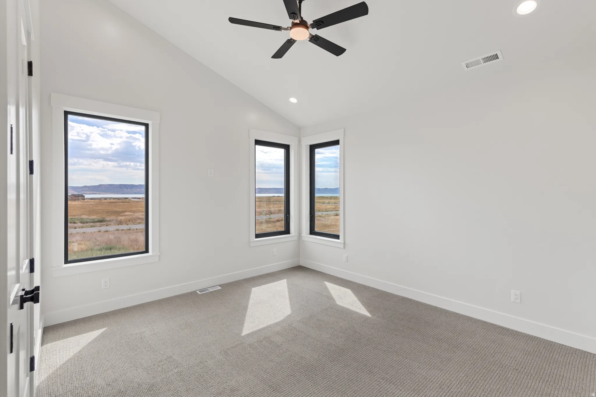 Vaulted ceiling with a ceiling fan, recessed lighting, and expansive windows