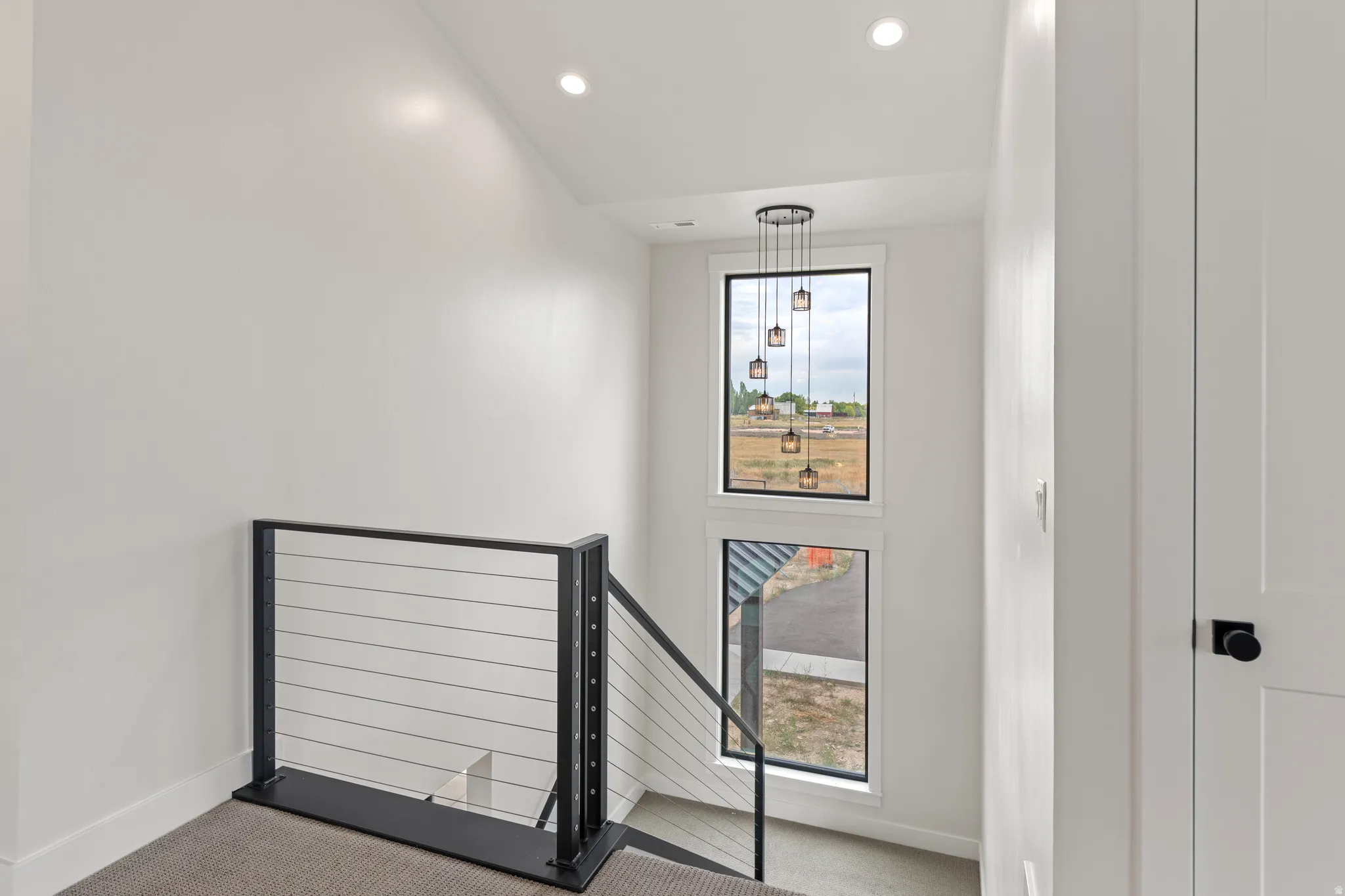 Modern cable railing system, recessed ceiling lighting, multi-pendant light fixture, and vertical window design