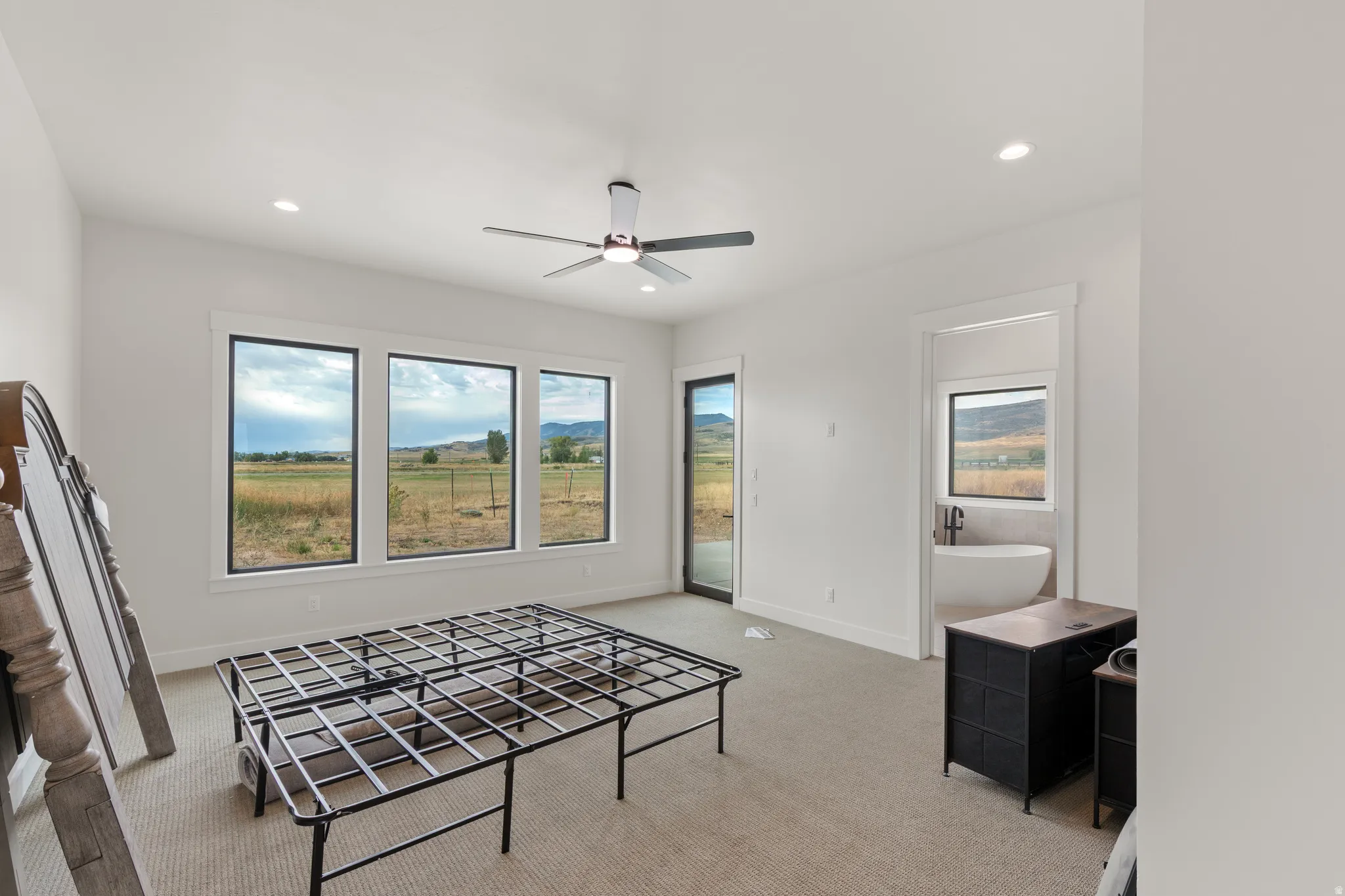 Recessed lighting, ceiling fan, carpeting, multiple large windows, and a sliding glass door