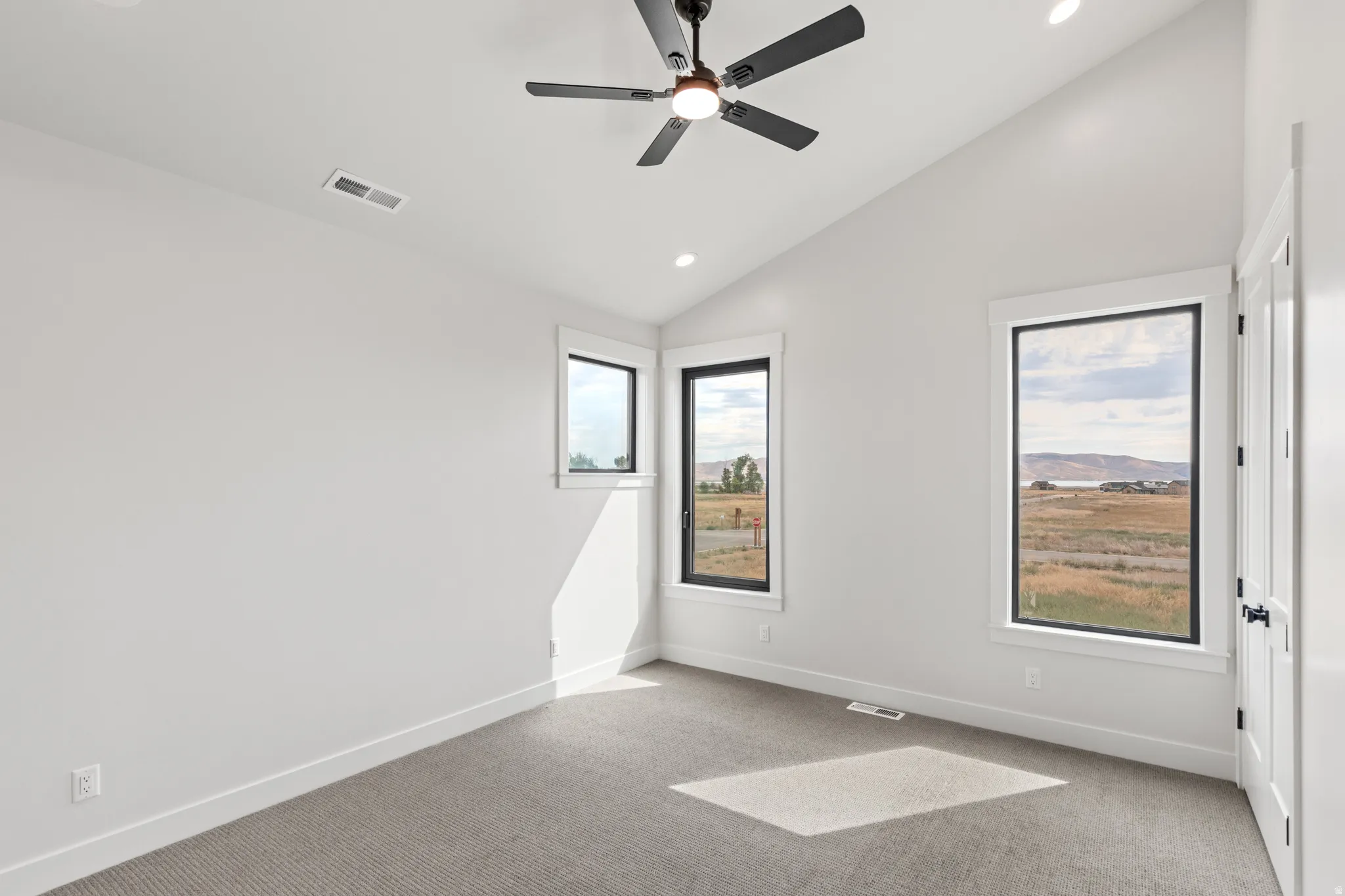 Vaulted ceiling featuring a ceiling fan with integrated lighting, recessed lighting, carpeting, and multiple windows