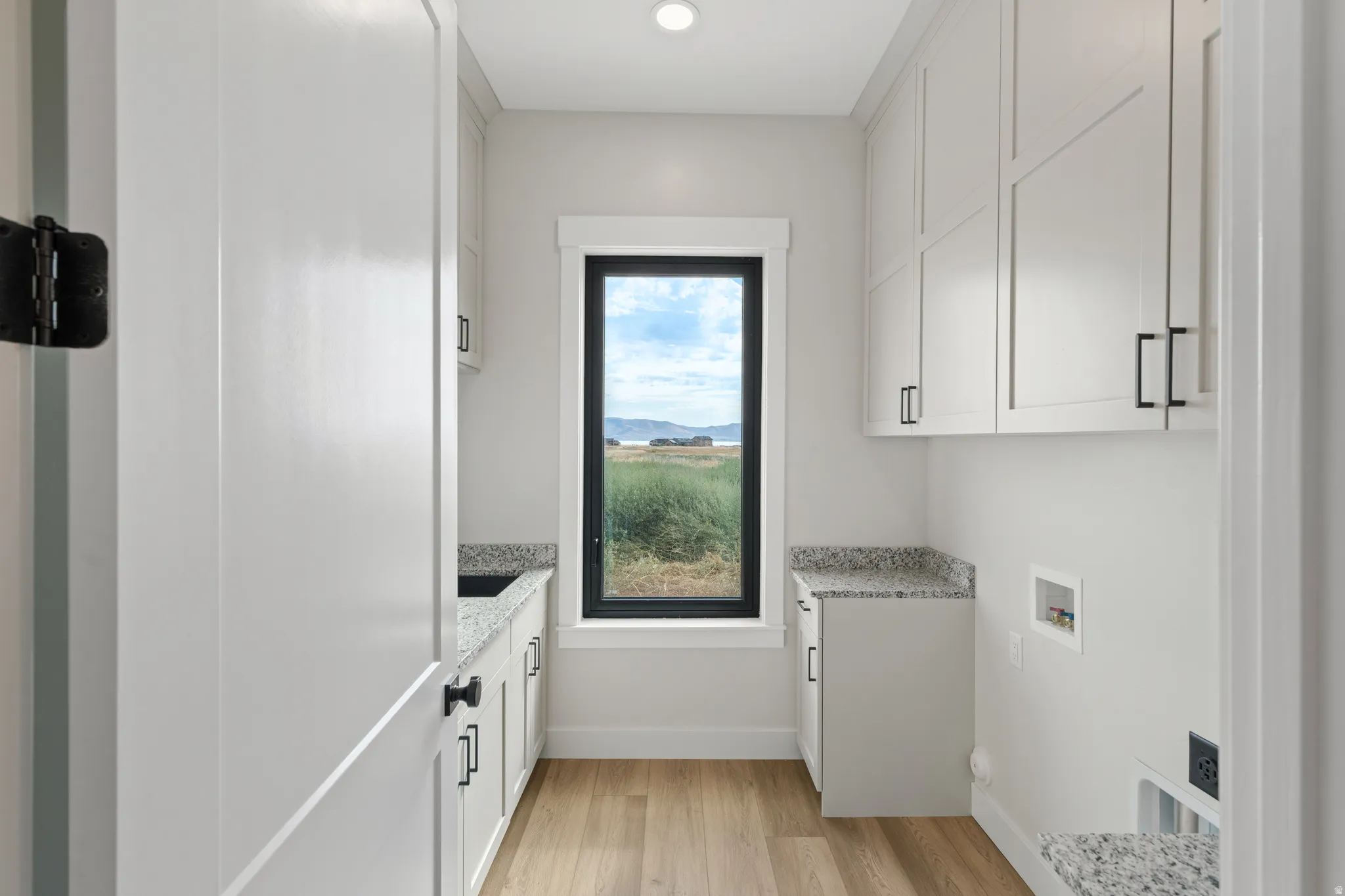 Built-in cabinetry with black hardware, wood-finish flooring, and light-toned countertops