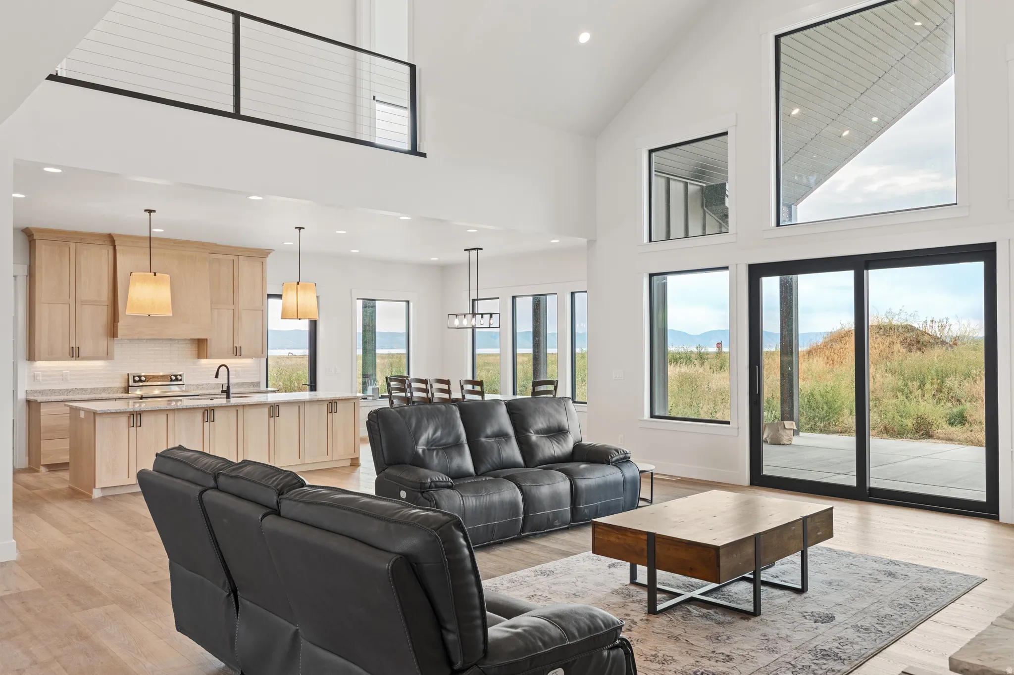 Vaulted ceilings, wood-finish flooring, full-height cabinetry, sliding glass door, and cable railing