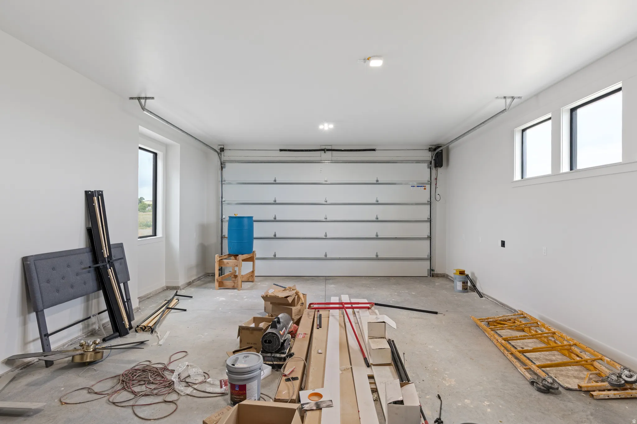 Concrete flooring, multiple windows, overhead lighting, and white walls