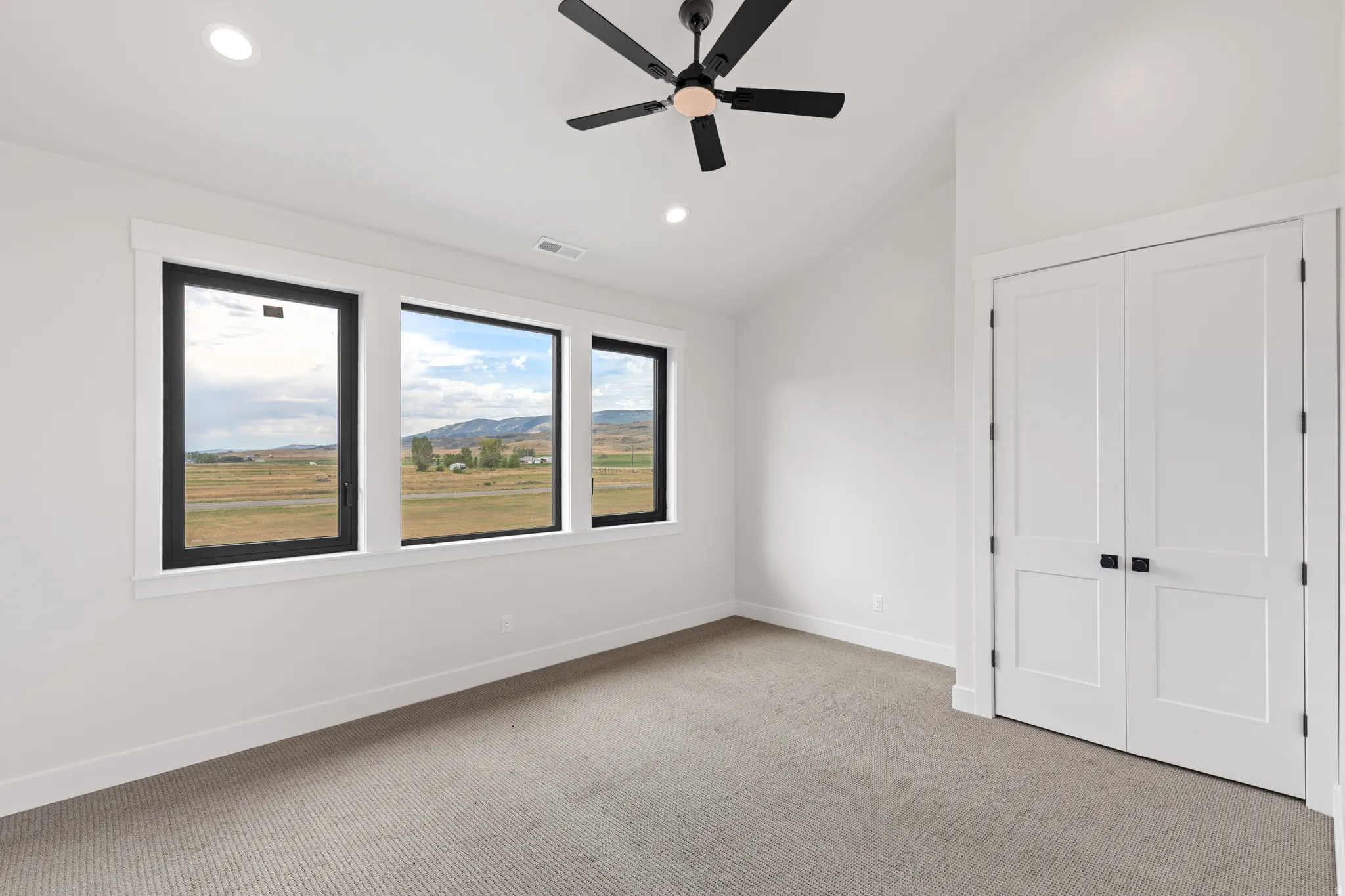 White walls with black-framed windows, a black ceiling fan, recessed lighting, and a neutral-toned carpet