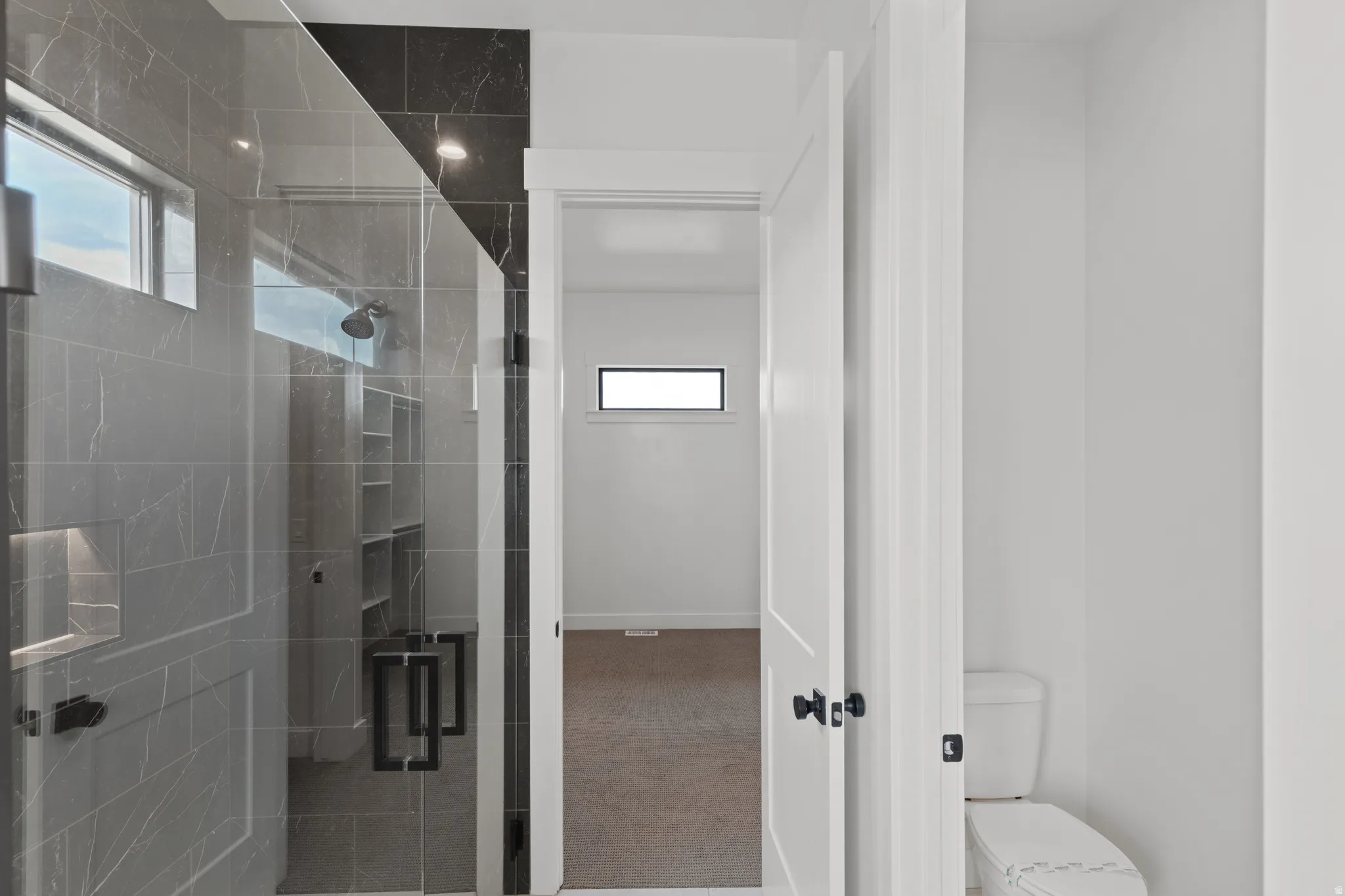 Walk-in shower with clear glass enclosure and contrasting dark tile