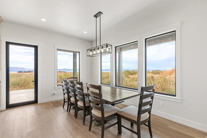 Wood-finish flooring, a contemporary linear chandelier, and abundant natural light illuminate this space