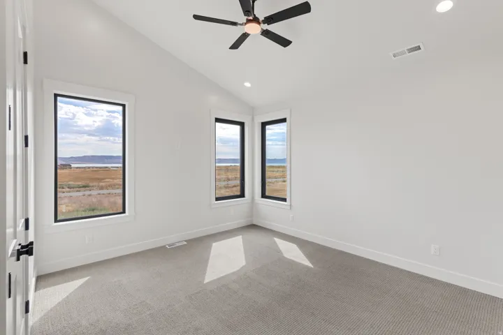 Vaulted ceiling with a ceiling fan, recessed lighting, and expansive windows