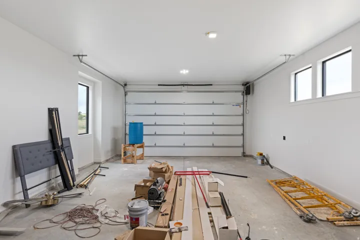Concrete flooring, multiple windows, overhead lighting, and white walls