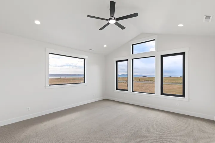Angled vaulted ceiling with recessed lighting, modern ceiling fan, multiple large windows, and carpeted flooring
