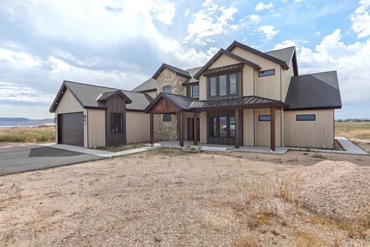 Contemporary exterior featuring vertical and horizontal siding, stone accents, a covered entry, an attached garage, and dark trim details