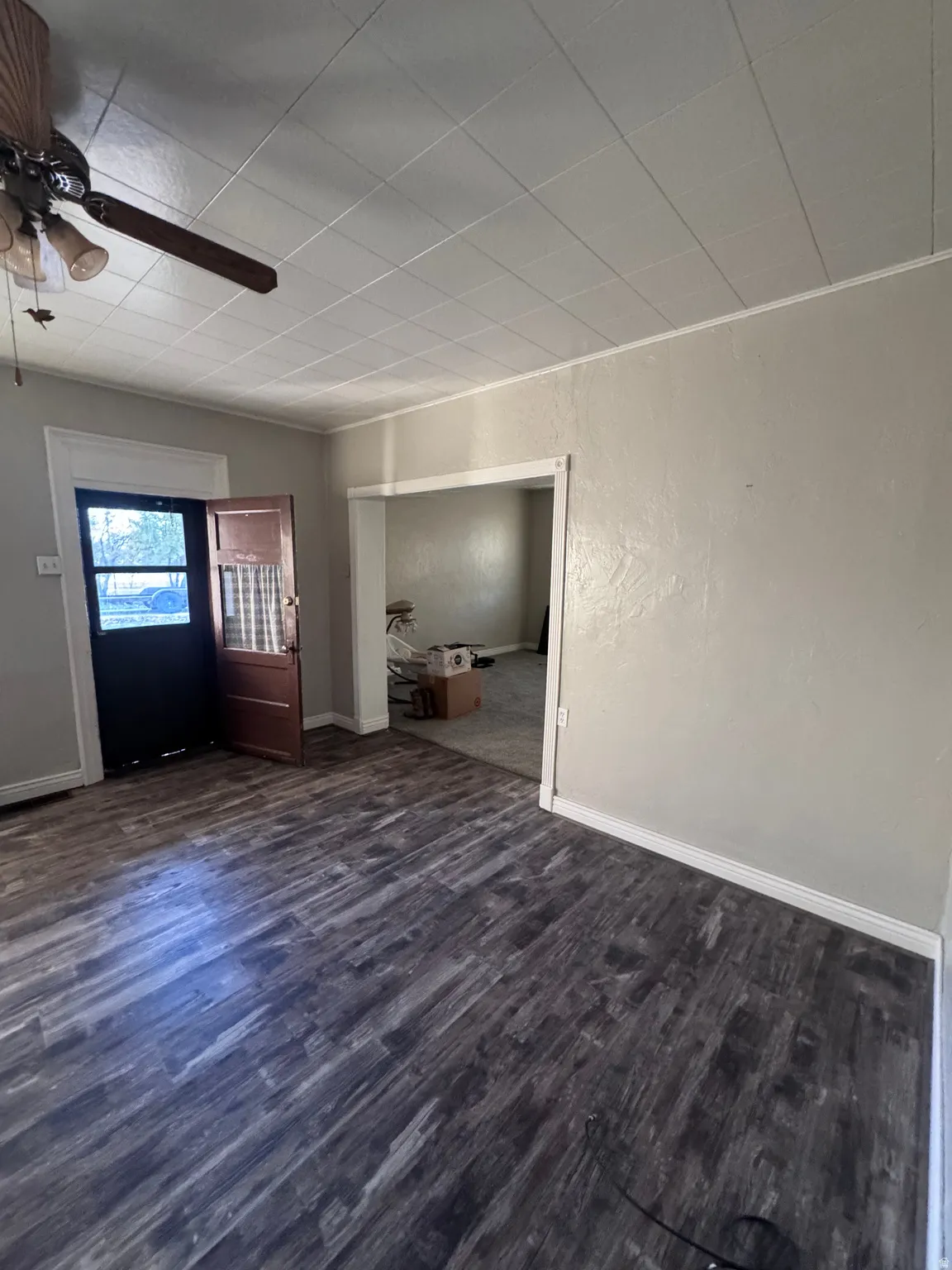 Unfurnished living room with ceiling fan, dark wood-type flooring, and a textured wall